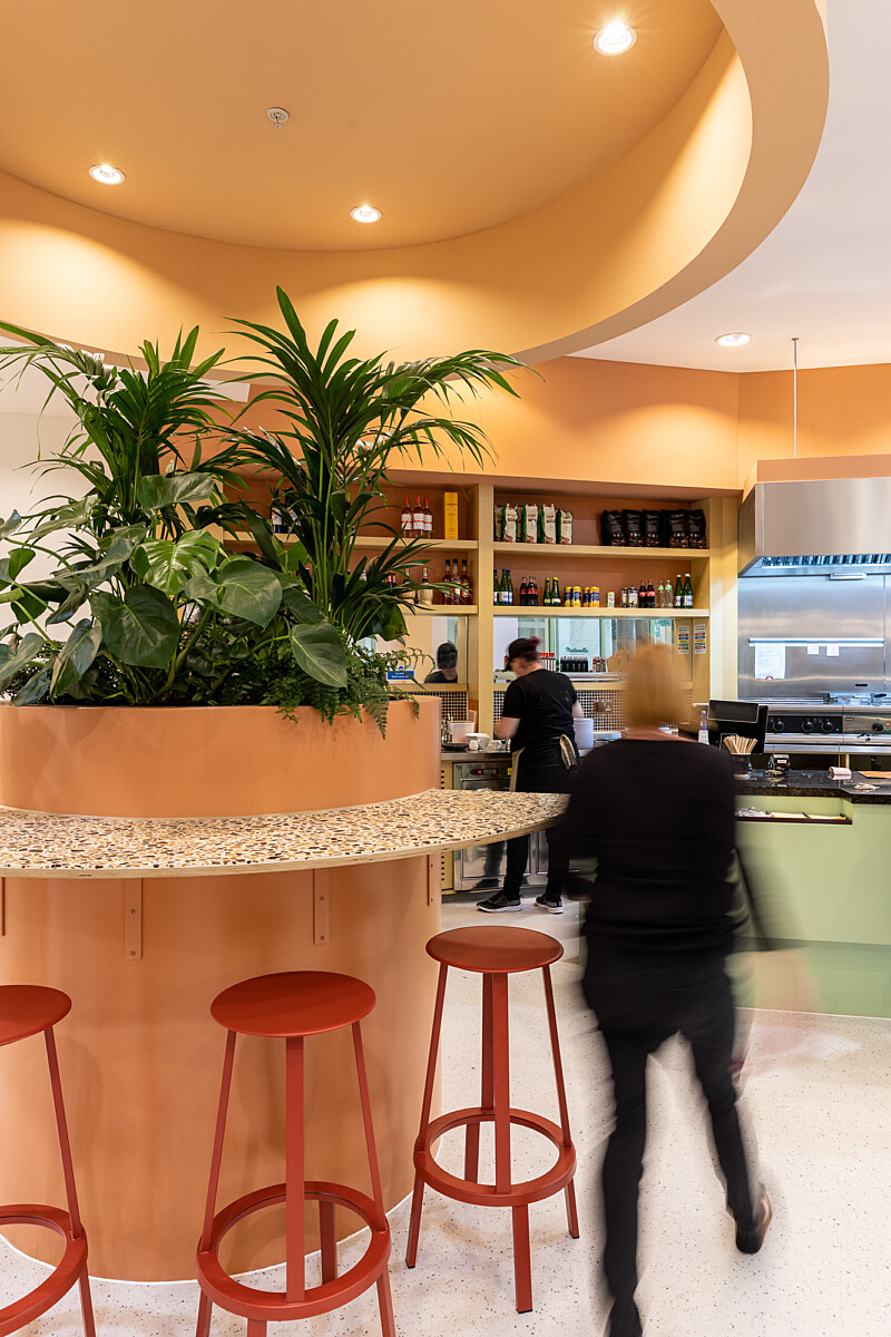 Red poseur height seating around circular planter in Matterello, italian restaurant interior
