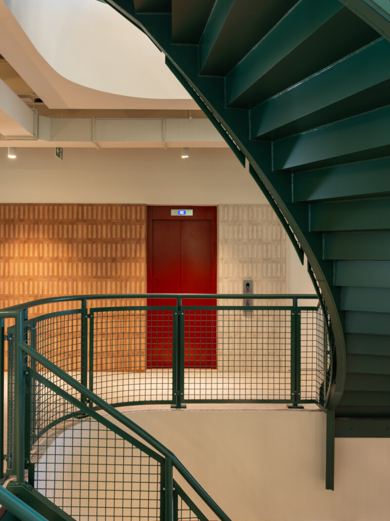 Green staircase, wall tile and red lift door detail at TMT Group HQ workspace