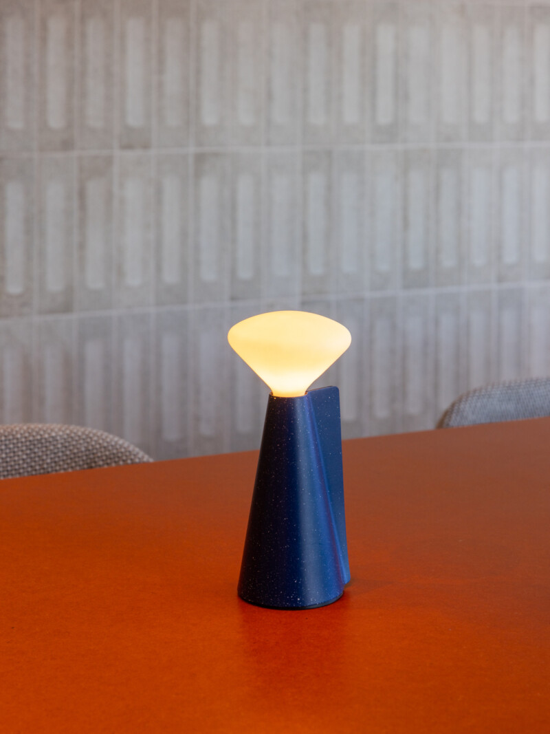 Designer lamp on red meeting table with tiled wall background at TMT Group HQ workspace